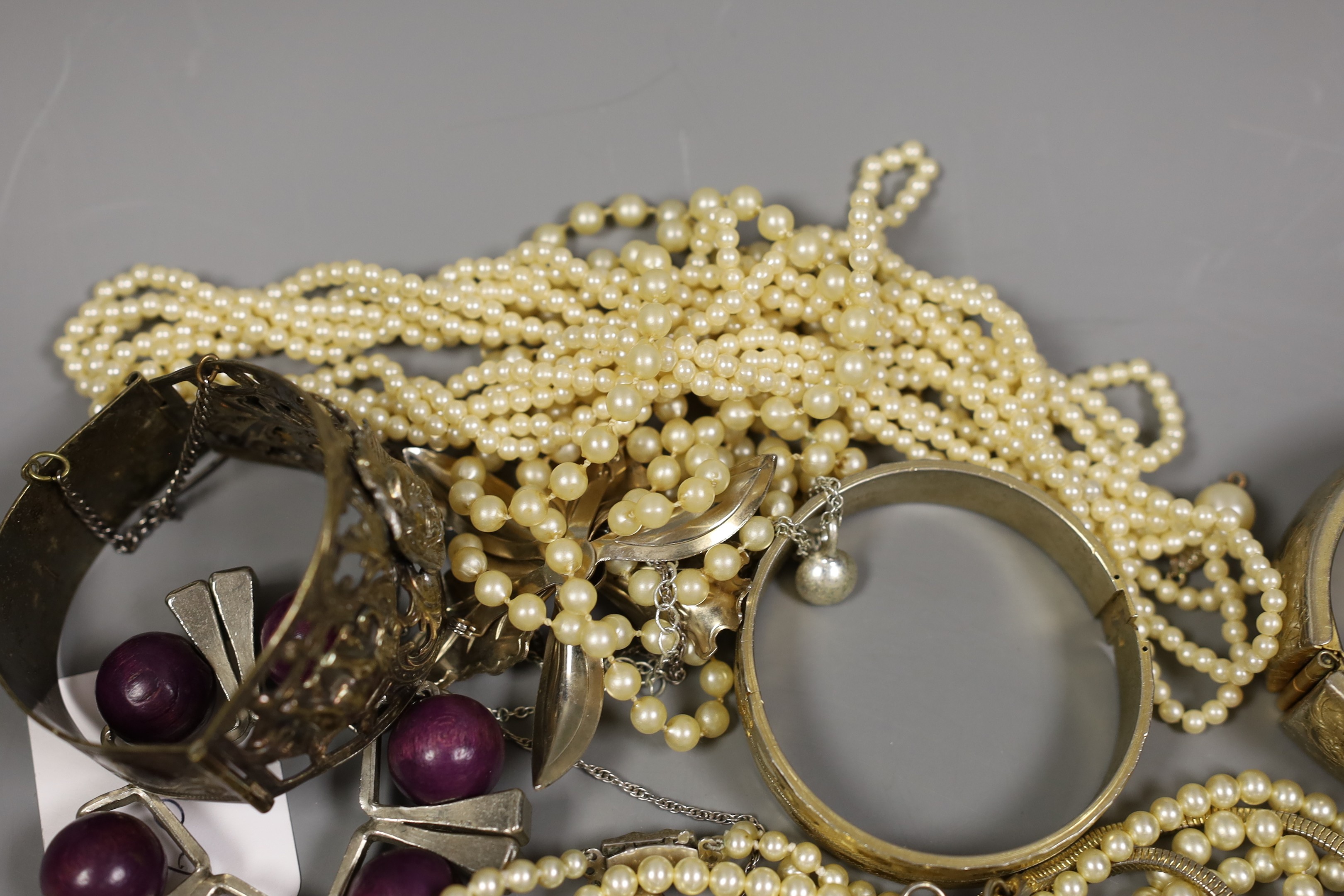 Assorted costume jewellery including a silver charm bracelet, hung with various charms including merry-go-round and bull.